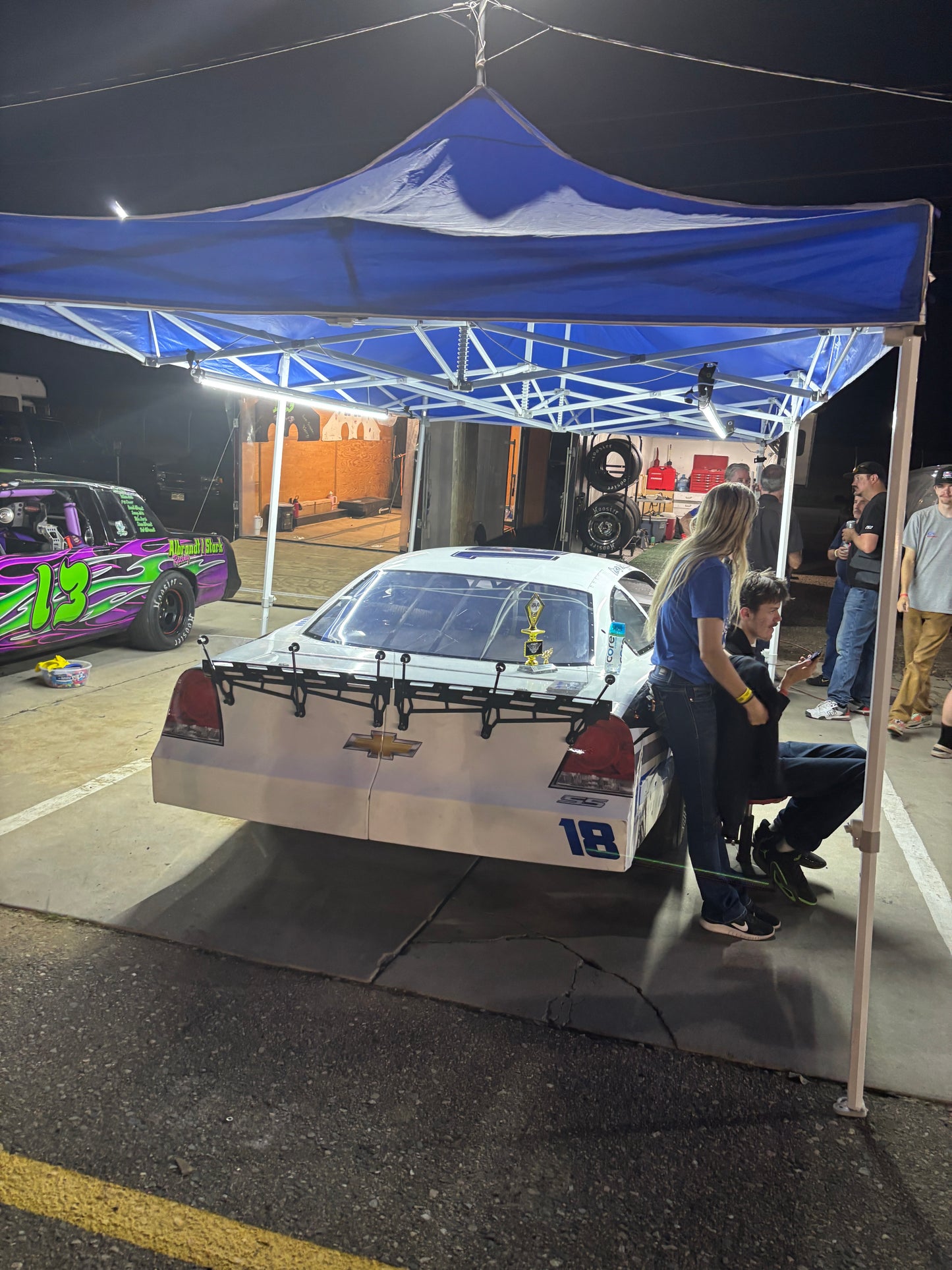 Car show or automotive event with cars on display and people around. Canopy Pit Lights Shining